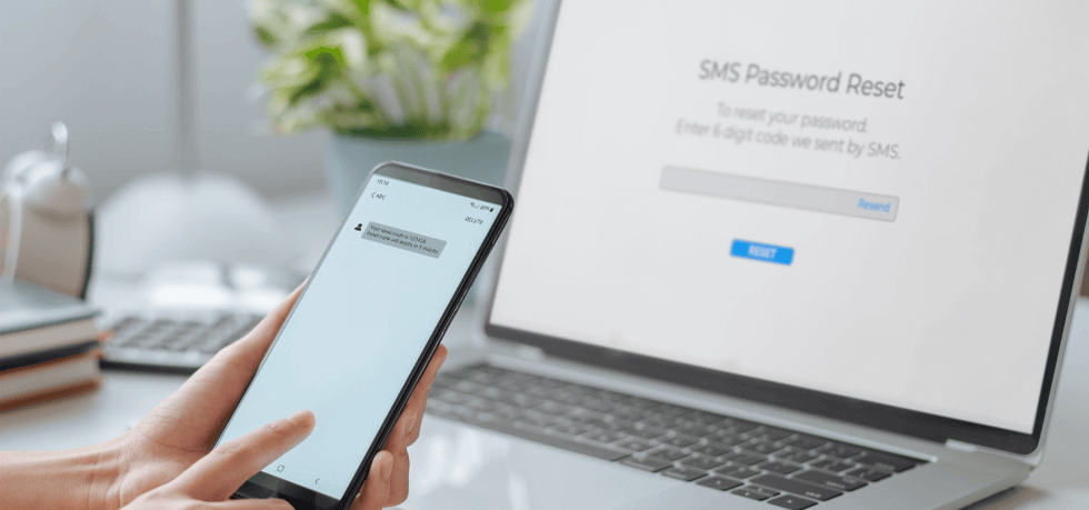 person logging on website on laptop and receiving verification code on their phone